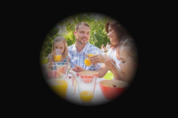 Simulation d'un glaucome avancé : seul le centre de la scène reste visible, une famille à table, tandis que les bords de l'image sont plongés dans le noir.
